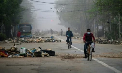 Des cyclistes passent des barricades érigées par les protestataires, à Rangoun le 11 mars 2021