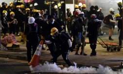 Un manifestant pro-démocratie couvre une grenade lacrymogÚne avec un cÎne de signalisation, le 28 juillet 2019 à Hong Kong