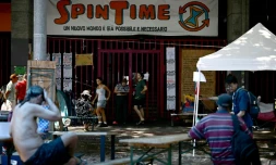 Des personnes récemment expulsées d'un centre social à Rome sont installées devant ses grilles fermées, le 11 août 2026