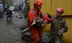 Des secouristes portent une fillette, restée ensevelie pendant des heures dans les décombres de sa maison détruite par les intempéries à Petropolis, au Brésil, le 23 mars 2024