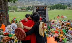 Des membres de la nation Mosakahiken Cree s'enlacent devant un mémorial aux 215 enfants autochtones dont les restes ont été trouvés près d'un pensionnat, le 4 juin 2021 à Kamloops, au Canada
