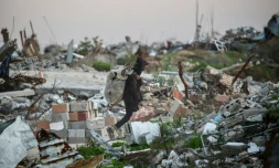 Un Palestinien transporte du bois à brûler dans les ruines du camp de réfugiés de Nousseirat, dans le centre de la bande de Gaza, le 31 décembre 2025