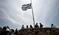 Des touristes près d'un drapeau grec sur l'Acropole à Athènes le 9 mai 2016