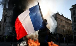Un manifestant avec un drapeau français devant un feu, le 17 octobre 2026 à Marseille