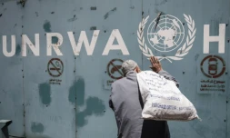 Un Palestinien devant l'emblème de l'Unrwa, l'agence de l'ONU pour les réfugiés palestiniens, devant ses bureaux de la ville de Gaza, le 31 juillet 2018