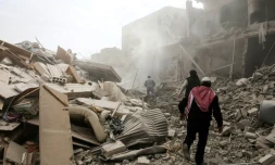 Des Syriens avancent au milieu des destructions provoquées par les raids aériens du régime syrien sur Sabqa, dans la Ghouta orientale près de Damas, le 6 février 2018