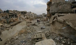 Des Syriens traversent une rue détruite du quartier al-Akroub d'Alep, le 17 décembre 2016