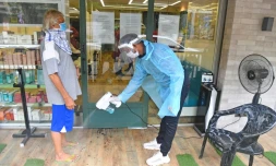 Un employé désinfecte les pieds d'un client avant qu'il entre dans un salon de coiffure, le 28 juin 2020 à Bombay, en Inde