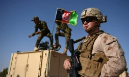 Des soldats afghans hissent le drapeau national près d'un Marine américain  à la base militaire de Lashkar Gah, dans la province du Helmand, le 28 août 2017
