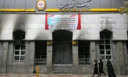 Des Iraniennes marchent devant une banque locale vandalisée durant les manifestations, à Chahriar, en banlieue ouest de Téhéran, le 20 novembre 2019