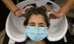 Un coiffeur espagnol lave les cheveux d'un client portant un masque à Burgos, le 4 mai 2020. 
