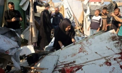 Une femme soulève une planche tachée de sang après une frappe qui a touché des tentes dans le centre de la bande de Gaza, le 9 novembre 2024