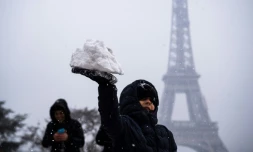 Un enfant joue avec de la neige devant la Tour Eiffel, le 5 février 2018 à Paris.
