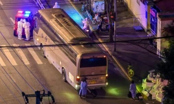 Des habitants de Shanghai avec des vĂȘtements de protection et leur valise (en bas) attendent de monter dans un autocar, le 19 avril 2022