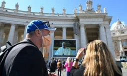 Un couple prend une photo du pape prononçant la prière dominicale depuis sa bibliothèque privée, et retransmise sur des écrans géants sur la plce Saint-Pierre de Rome, le 8 mars 2020, en raison de l'épidémie du nouveau coronavirus