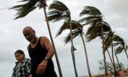 A couple walks through a debris-covered road in Fajardo, Puerto Rico
