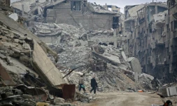 Des civils syriens marchent le long d'immeubles détruits par les bombardements du régime dans la ville rebelle, ancien fief rebelle dans la Ghouta orientale, le 30 mars 2018