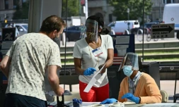 Des employées et volontaires d'un bureau de vote portent des équipements de protection contre le nouveau coronavirus lors de la primaire démocrate de New York, le 23 juin 2020 au Musée de Brooklyn