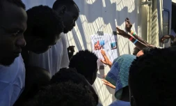 Des migrants recueillis par le navire Ocean Viking lisent des articles de presse les concernant, le 21 août 2019