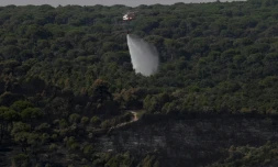 Un hélicoptère de lutte contre les incendies largue de l'eau pour rafraîchir une zone touchée par des feux de forêt à l'ouest de Madrid, le 28 juillet 2026