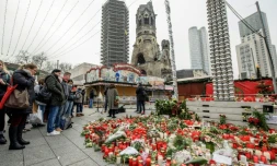 Des personnes se recueillent devant un parterre de fleurs et des messages en hommage aux victimes d'une attaque près d'un marché de Noël à Berlin, le 21 décembre 2016 en Allemagne