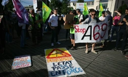 Des opposants au projet d'autoroute A69 entre les villes de Castres et de Toulouse se rassemblent à côté d'une pancarte portant l'inscription "Résistance, l'État force le passage" lors d'un rassemblement devant la gare de Toulouse, dans le sud-ouest de la France, le 28 mai 2025