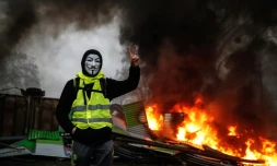 Un manifestant porte un gilet jaune et un masque prÚs d'une barricade en feu, le 1er décembre 2018 à Paris
