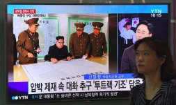 Une femme passe à Séoul devant des écrans montrant le leader nord-coréen Kim Jong-Un le 15 août 2017 
