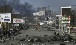 Habitants d'Irpin marchant à côté d'un cadavre pour évacuer la ville, le 10 mars 2022 en Ukraine