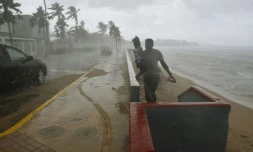 Un homme portant sa fille court pour échapper à la pluie et aux rafales de vent à l'approche de l'ouragan Maria, le 19 septembre 2017 à San Juan, à Porto Rico