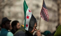 Un homme tient les drapeaux américains et syriens lors d'une manifestation devant la Maison Blanche le 15 mars 2014
