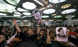 Des personnes en deuil tiennent des affiches du président iranien Ebrahim Raïssi lors d'une cérémonie funéraire à la mosquée Mosalia à Téhéran, le 21 mai 2024