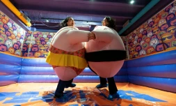 Des visiteuses, en costumes rembourrés, se battent dans l'"arène de sumo" au musée du rire HaHaHouse à Zagreb, le 21 janvier 2025 en Croatie
