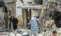 Une femme se fraye un chemin à travers les décombres sous le regard d'un soldat libanais, sur le site d'un immeuble résidentiel touché la veille par une frappe israélienne près de la ville de Burj al-Shamali, au sud de Tyr, le 27 mai 2026