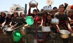 Des Palestiniens affamés attendent de recevoir une ration de soupe de lentilles lors d'une distribution alimentaire à Gaza, le 2 août 2025