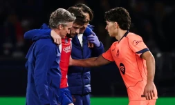 L'attaquant du PSG Khvicha Kvaratskhelia (c) quitte la pelouse aprĂšs s'ĂȘtre blessĂ© au genou droit lors du match contre le FC Barcelone, rĂ©confortĂ© par Xavi Espart, le 20 octobre 2026 au Parc des Princes