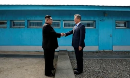 Moon Jae-in (d) et Kim Jong Un se serrent la main sur la ligne de démarcation avant le début du sommet, le 27 avril 2018 à Panmunjom