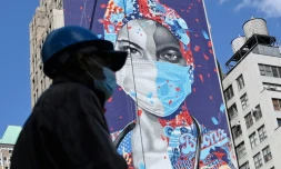 Un ouvrier masqué passe devant une fresque murale en l'honneur des soignants de la pandémie, le 7 mai 2020 à Manhattan