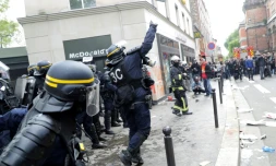 Un CRS lance une grenade lacrymogÚne contre des manifestants en marge du défilé syndical du 1er mai 2018 à Paris