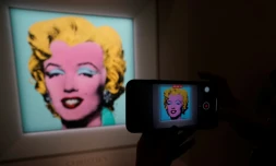 Au siÚge de la maison d'enchÚres Christie's à New York le 21 mars 2022, un journaliste photographie le portrait de Marilyn Monroe "Shot Sage Blue Marilyn" par Andy Warhol, estimé à 200 millions de dollars