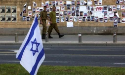Des soldats passent devant un mur du ministÚre de la Défense à Tel Aviv, le 16 octobre, sur lequel des photos des Israéliens enlevés par le Hamas le 7 octobre 2023 ont été collées