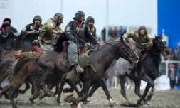 Des cavaliers des équipes de Kandahar (en noir) et Kunduz s'affrontent lors du championnat de bouzkachi à Kaboul, le 6 mars 2022