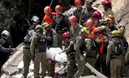 Image tirée d'une vidéo d'AFPTV montrant des équipes de secours  sortant les corps de victimes des décombres d'un immeuble résidentiel détruit par une attaque de missile iranienne dans la ville de Haïfa, dans le nord d'Israël, le 6 avril 2026