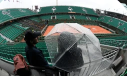 Une personne s'abrite sous un parapluie en attendant le début des matches (finalement annulés) en raison d'une pluie persistante  sur Roland-Garros, le 30 mai 2016