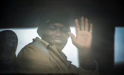 Un homme salue par la fenêtre d'un bus qui transporte des migrants, principalement soudanais, de Calais à des centre de "répit", le 27 octobre 2015