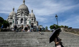 Une touriste se protĂšge du soleil avec un parapluie devant la basilique du SacrĂ©-CĆur Ă Paris, le 6 juillet 2026, lors d'une vague de chaleur en France