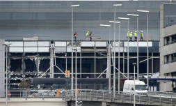 Des ouvriers marchent sur le toit de l'aéroport de Bruxelles à Zaventem le 23 mars 2016 au lendemain des attentats terroristes dans la capitale belge