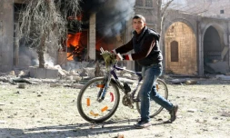 Un habitant d'un quartier assiégé d'Alep-Est passe devant une maison en feu, le 19 novembre