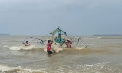 Des Philippins mettent en sécurité un bateau de pêche sur la côte à Borongan, dans le centre des Philippines, le 2 décembre 2019 à l'approche du typhon Kammuri
