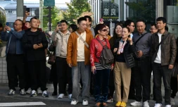 Un groupe de touristes chinois attend pour traverser une rue dans le quartier commerçant de Ginza, à Tokyo, le 16 novembre 2025